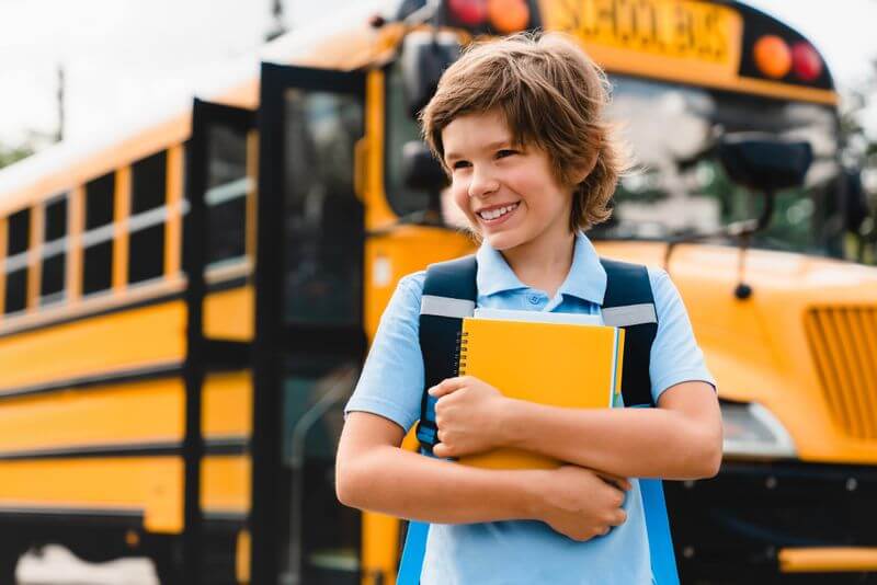 Child holding a book outside of school